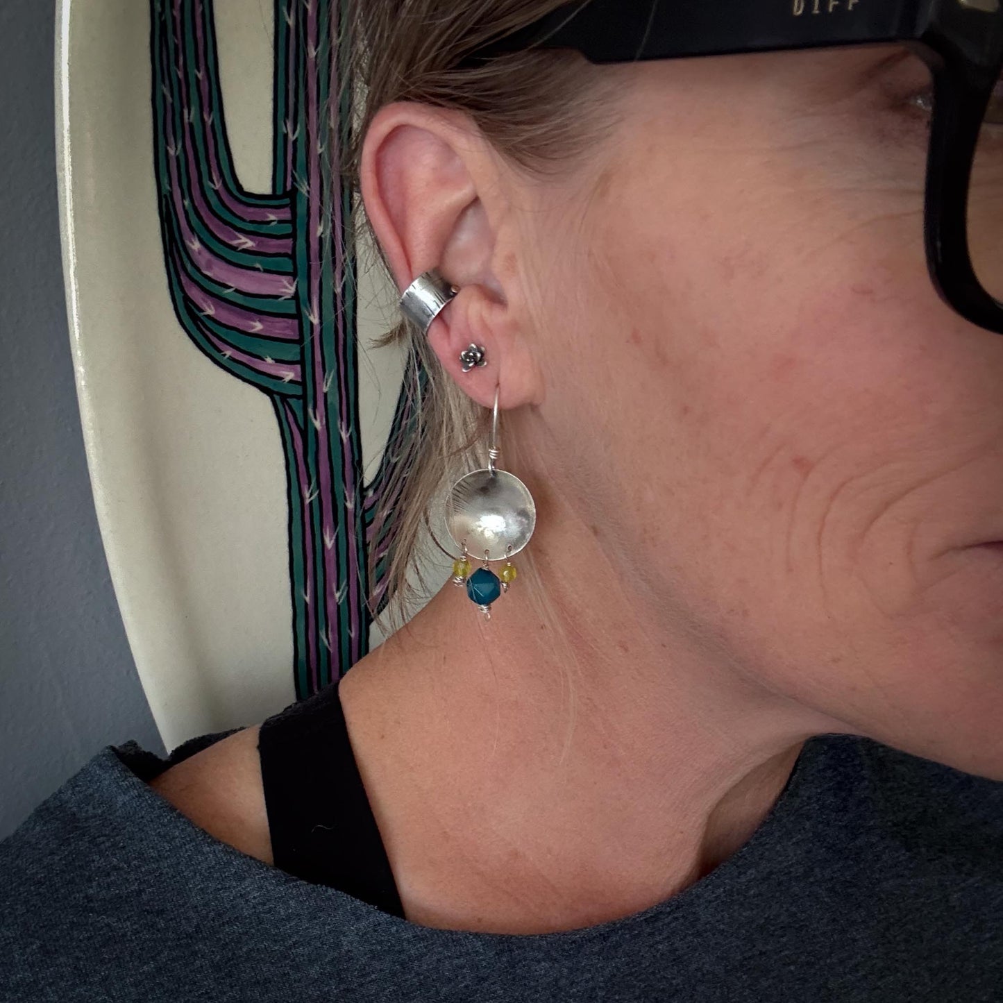 Close-up of a person wearing a silver earring with a blue bead.