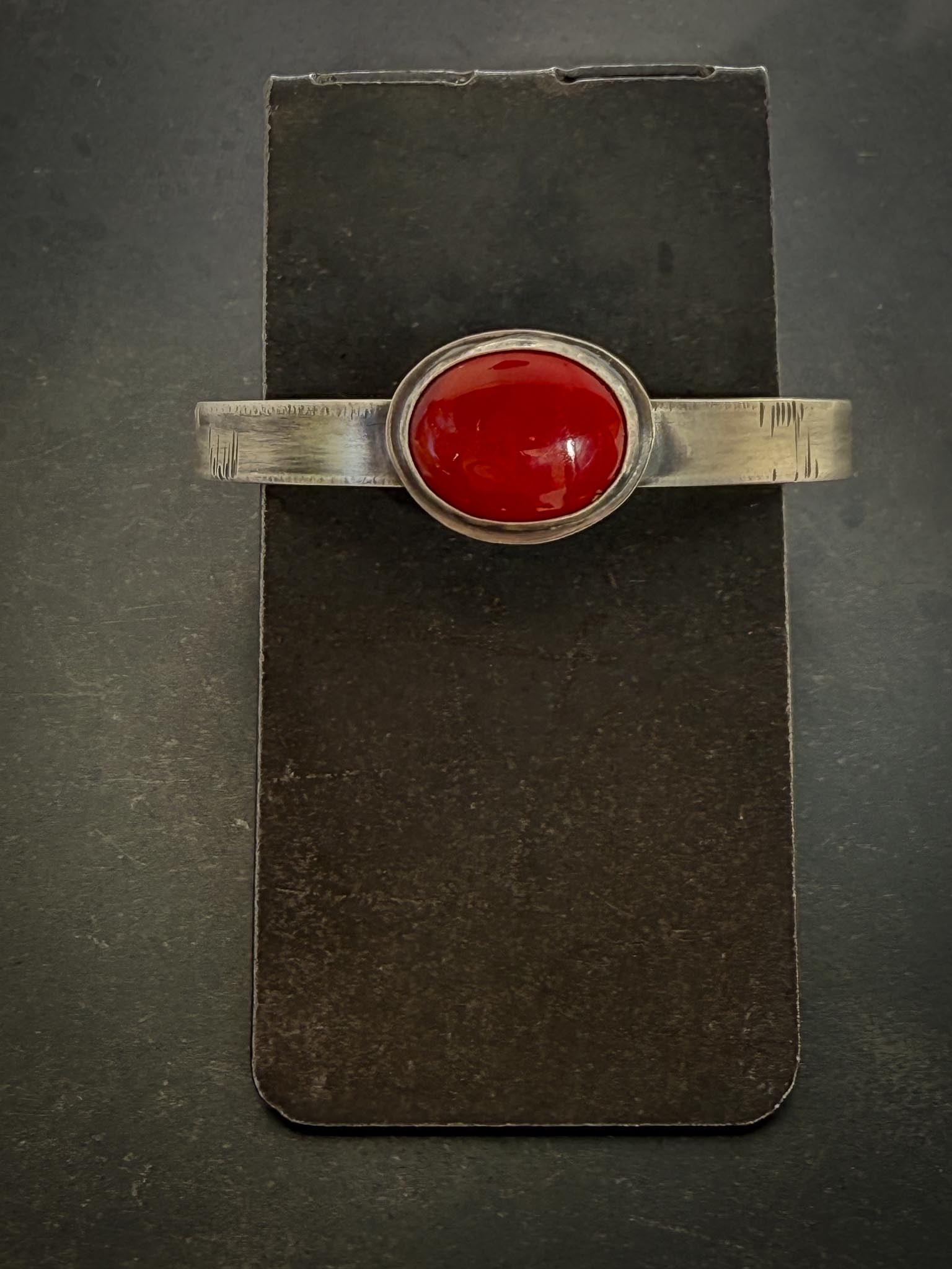 Silver ring with a red stone on a dark gray background