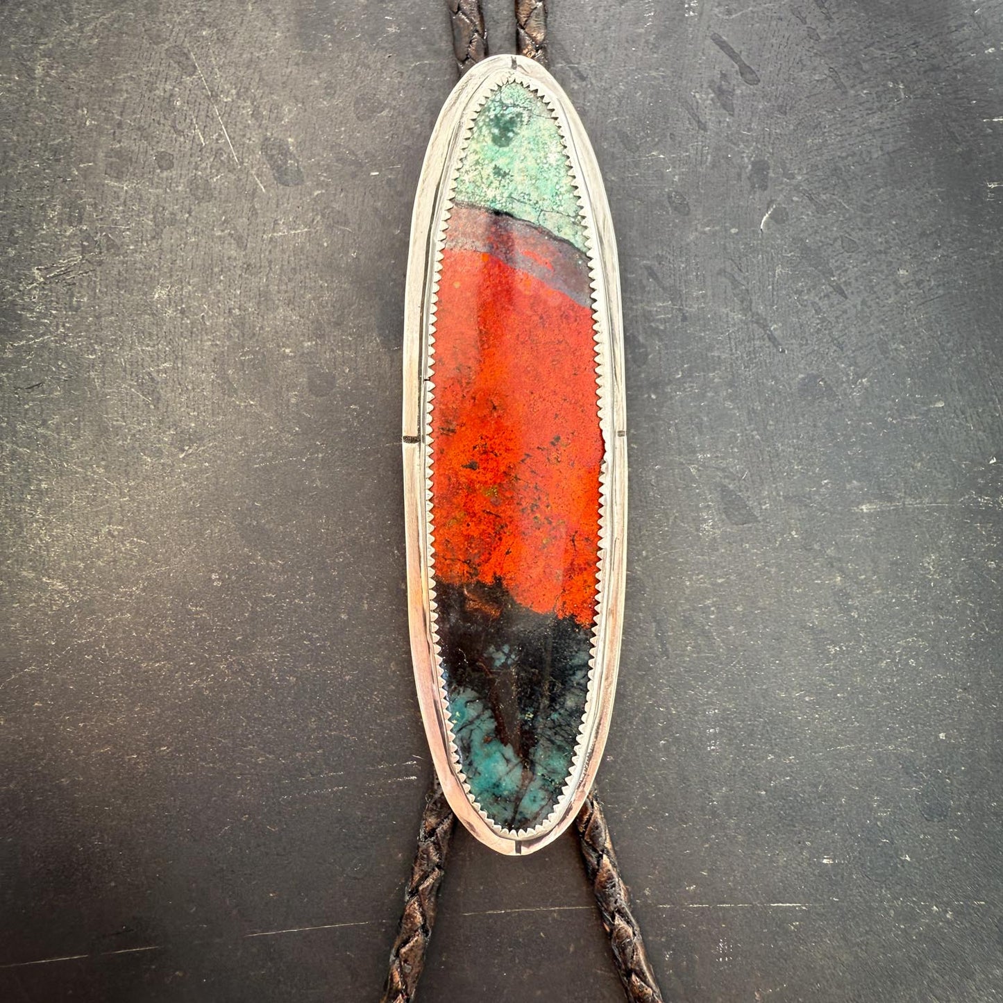 Bolo tie with a colorful oval stone on a dark gray background