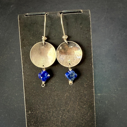 Pair of silver earrings with blue beads on a dark background