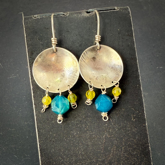 Silver earrings with blue and yellow beads on a black card