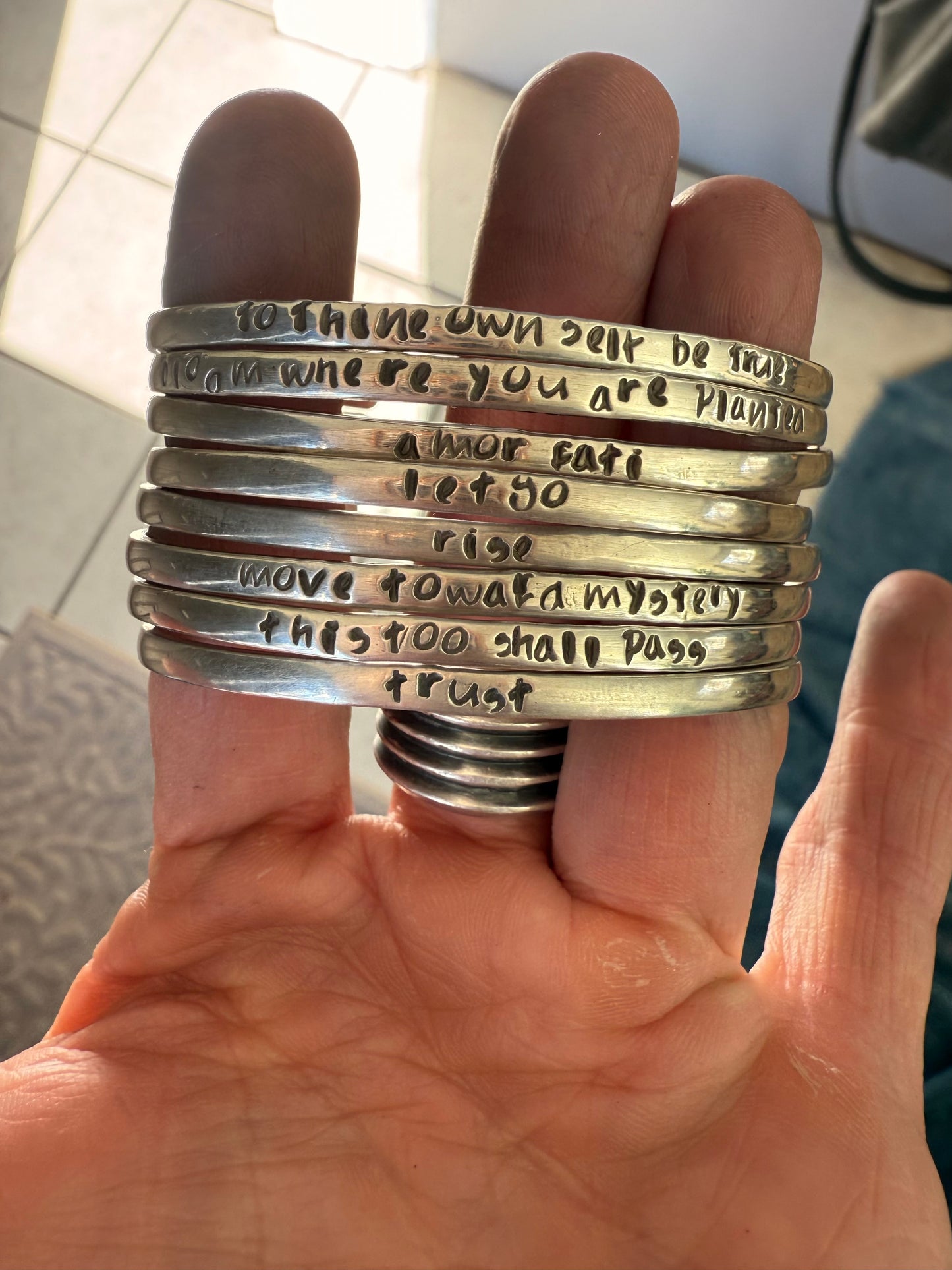 Stack of silver rings with engraved text on a hand