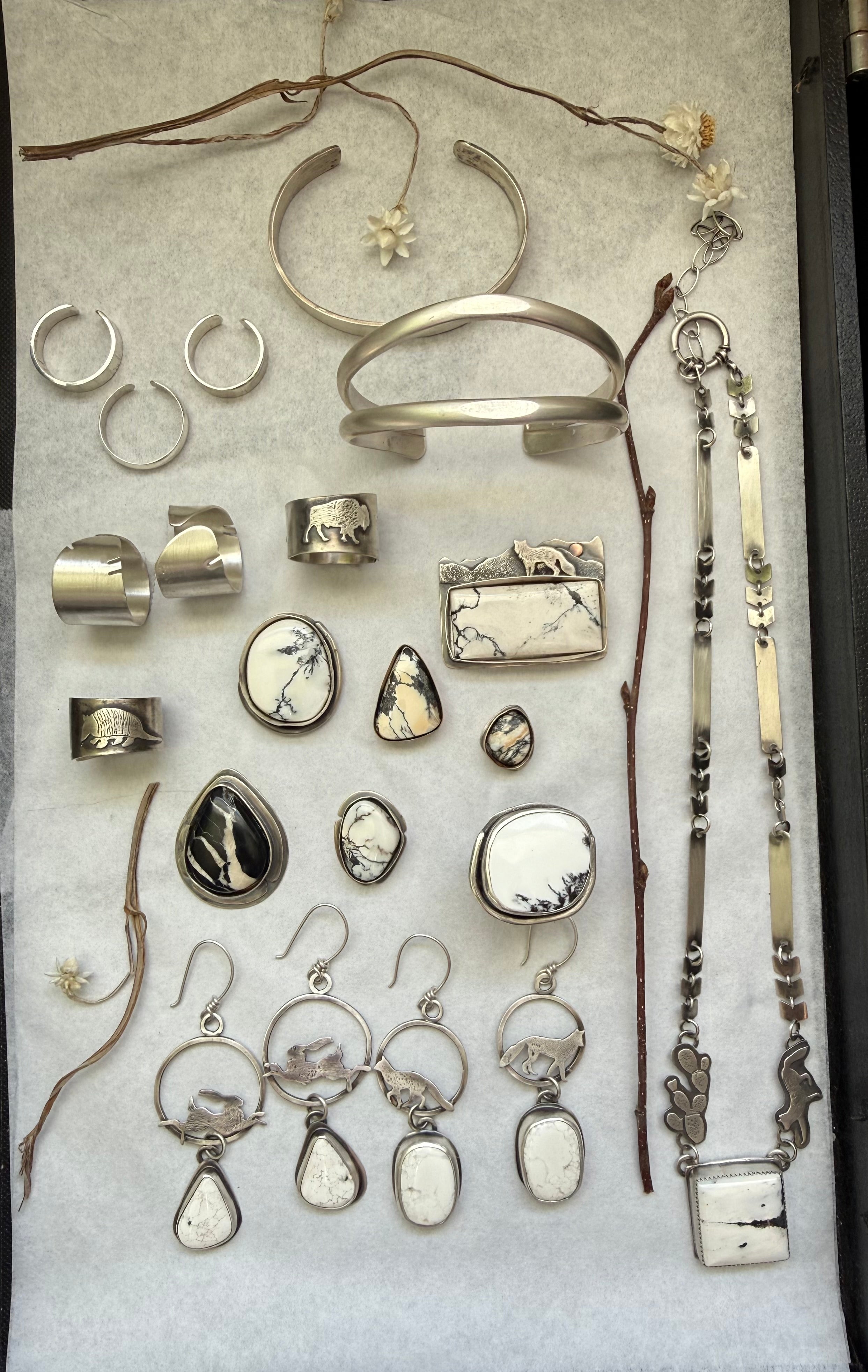 Collection of silver jewelry including rings, earrings, and necklaces on a white background.