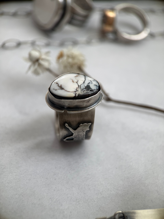 Silver ring with a black and white stone on a gray surface