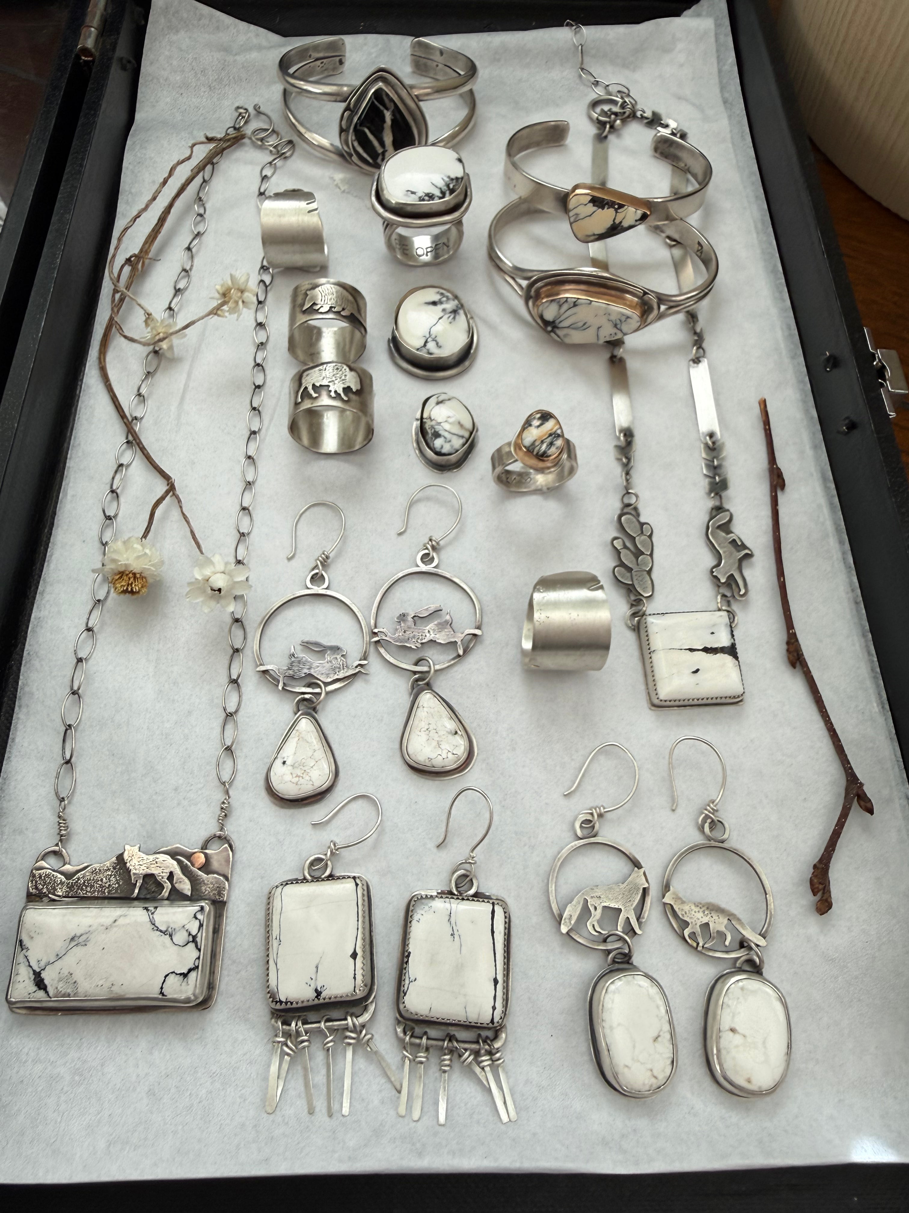 Collection of silver jewelry including rings, necklaces, and earrings on a white surface.