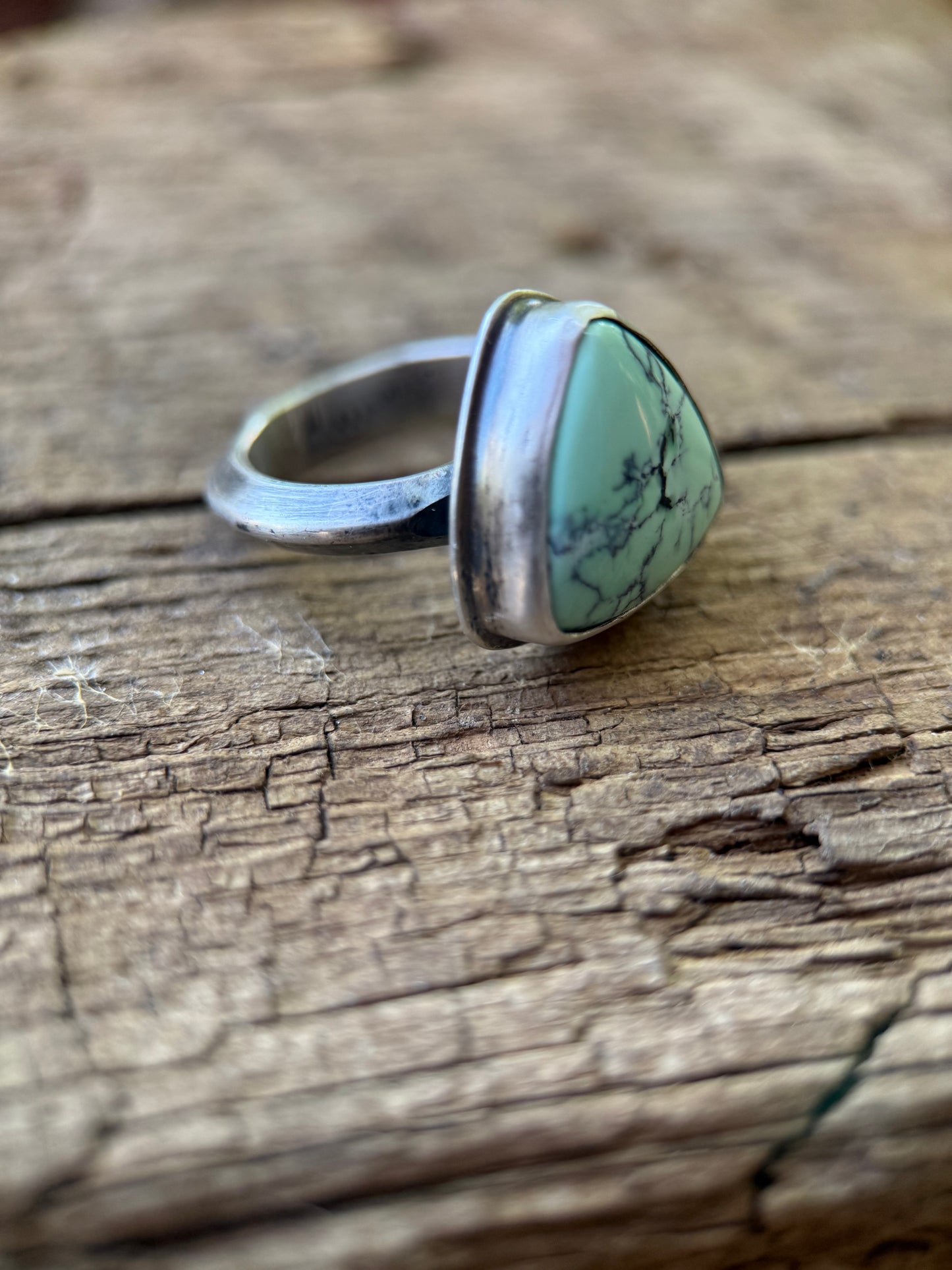 Silver ring with a variscite stone on a wooden surface