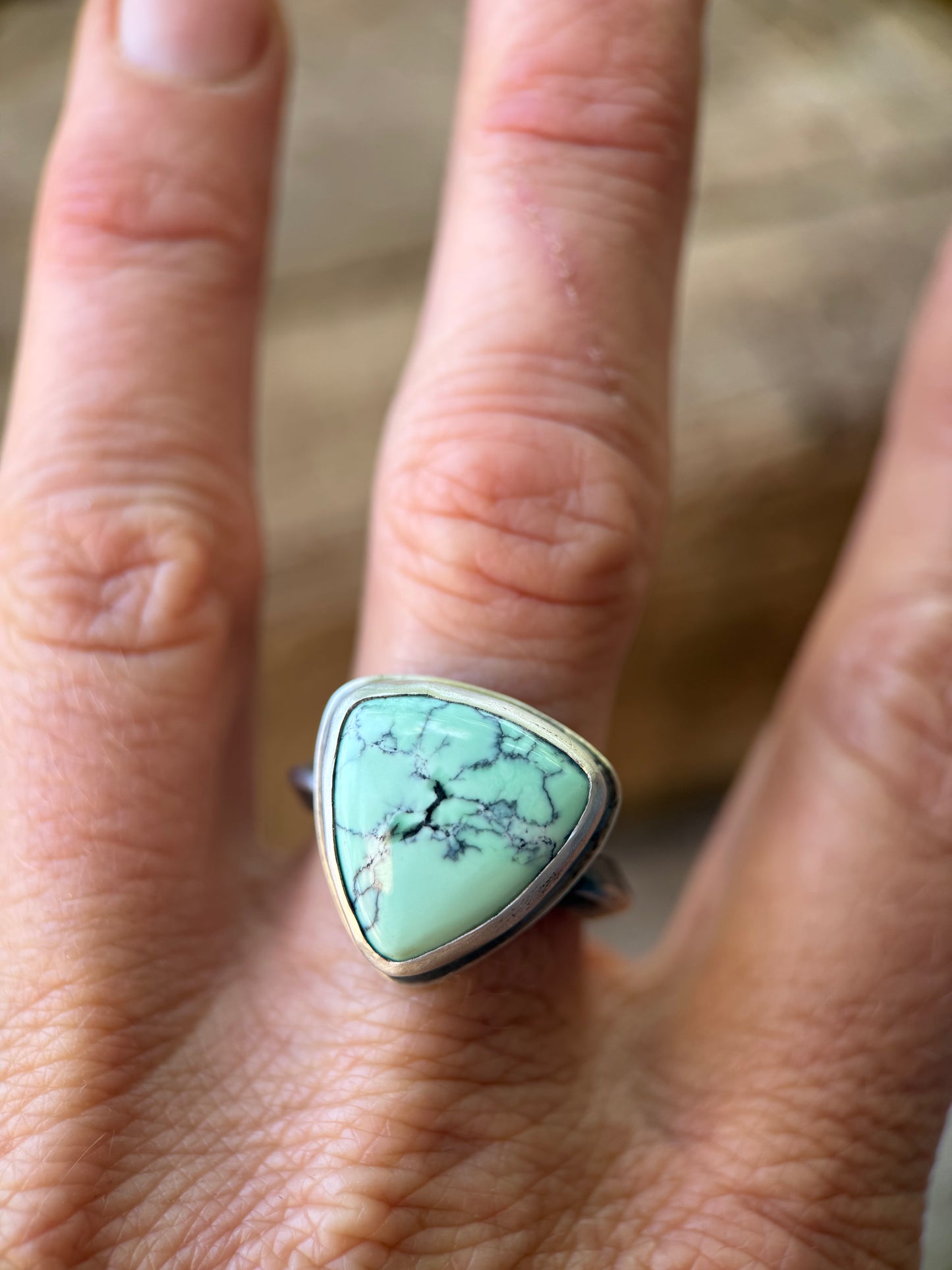 Variscite  ring on a finger with a blurred background