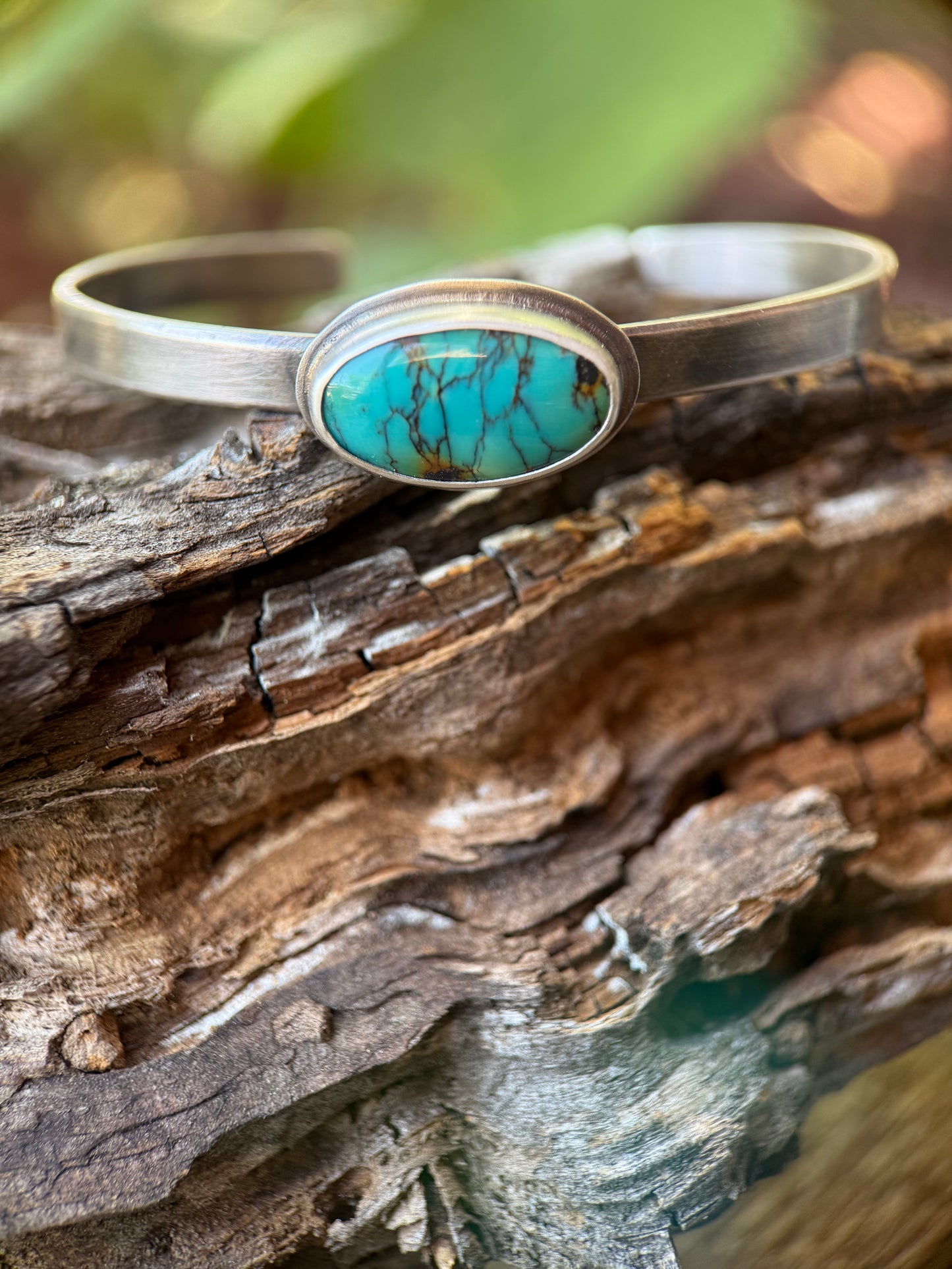 Silver bracelet with a turquoise stone on a wooden surface