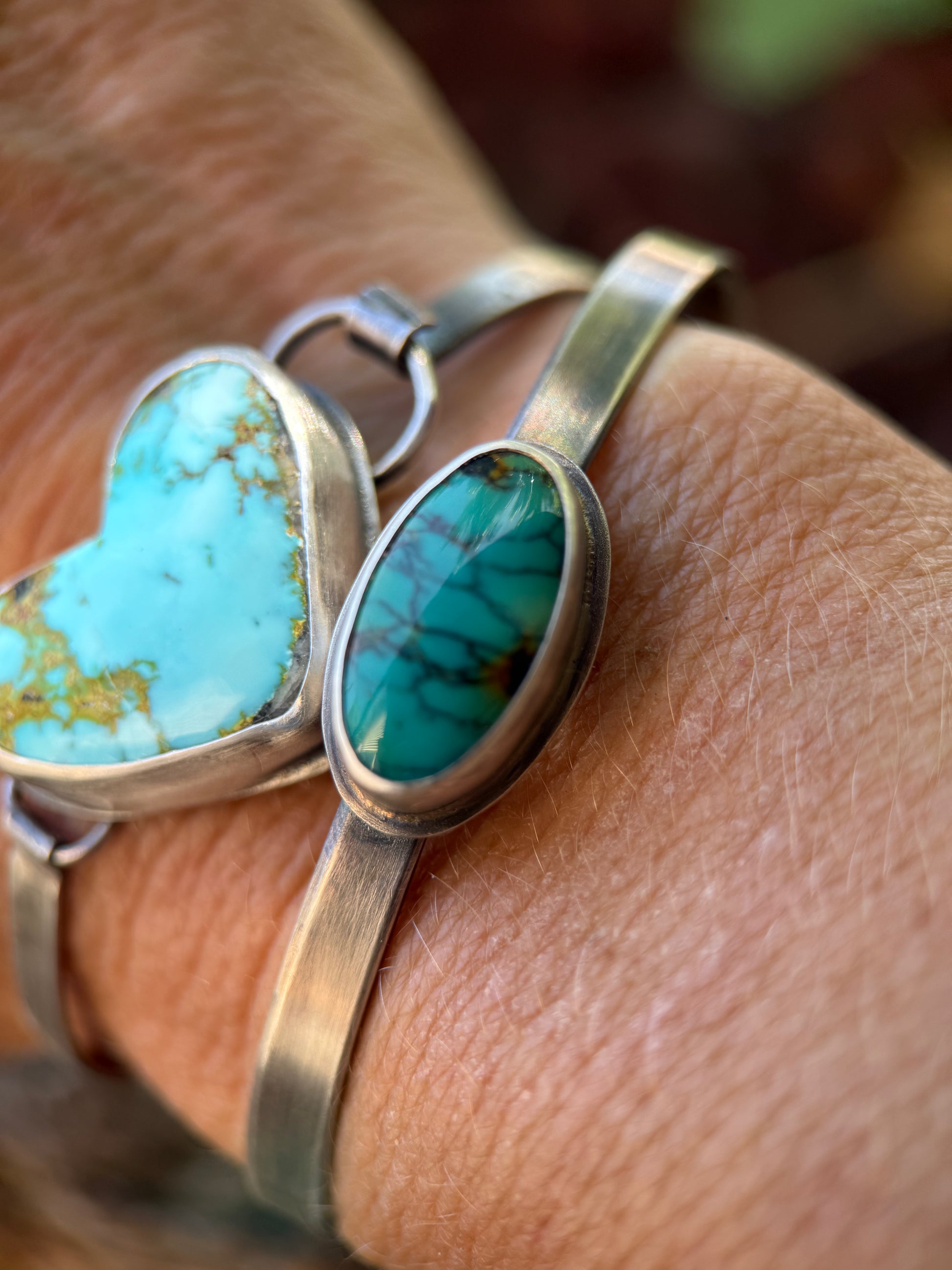 Turquoise stone cuff bracelets on a person's wrist with a blurred background