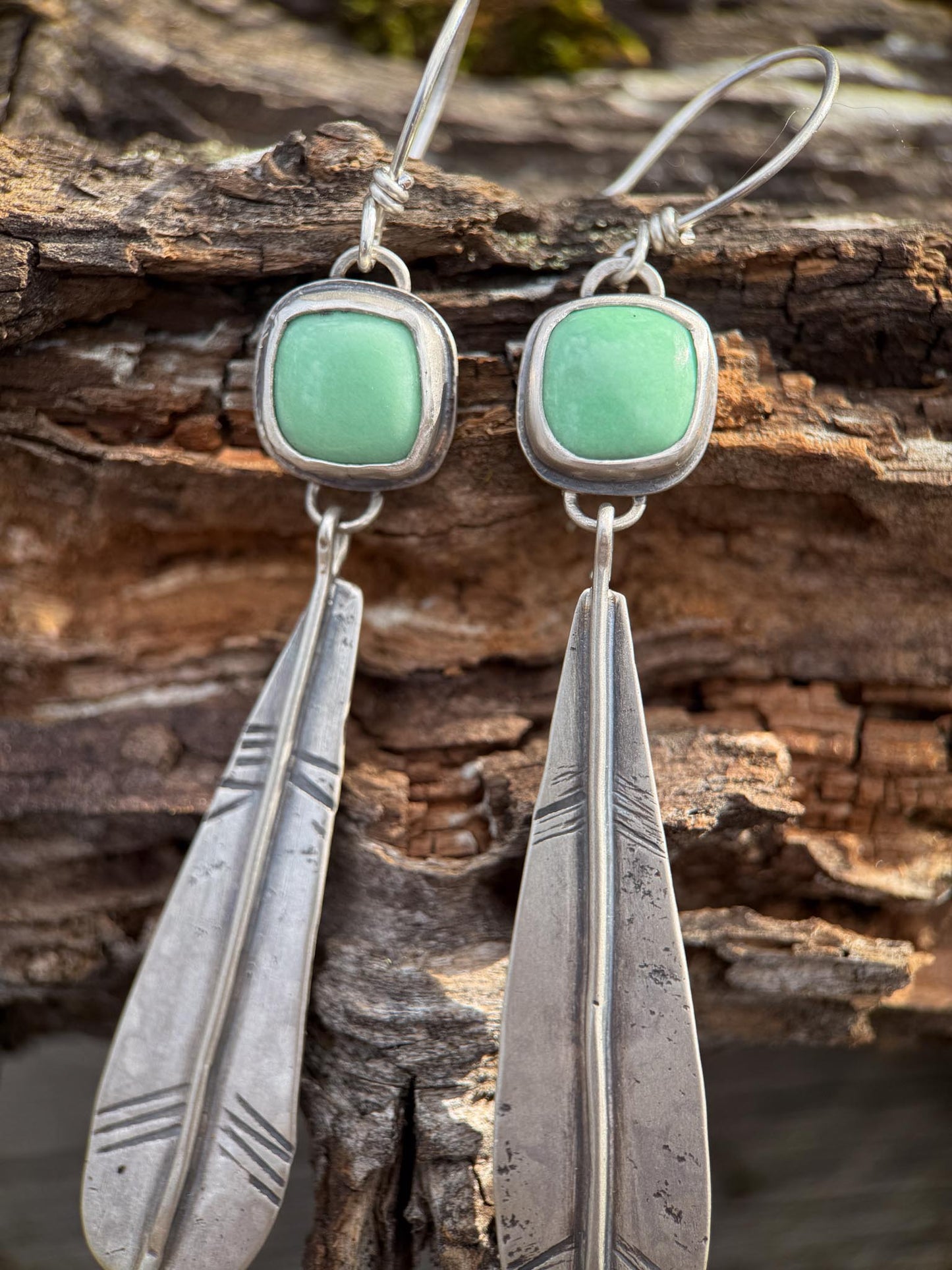 Silver earrings with green variscite stones on a wooden background