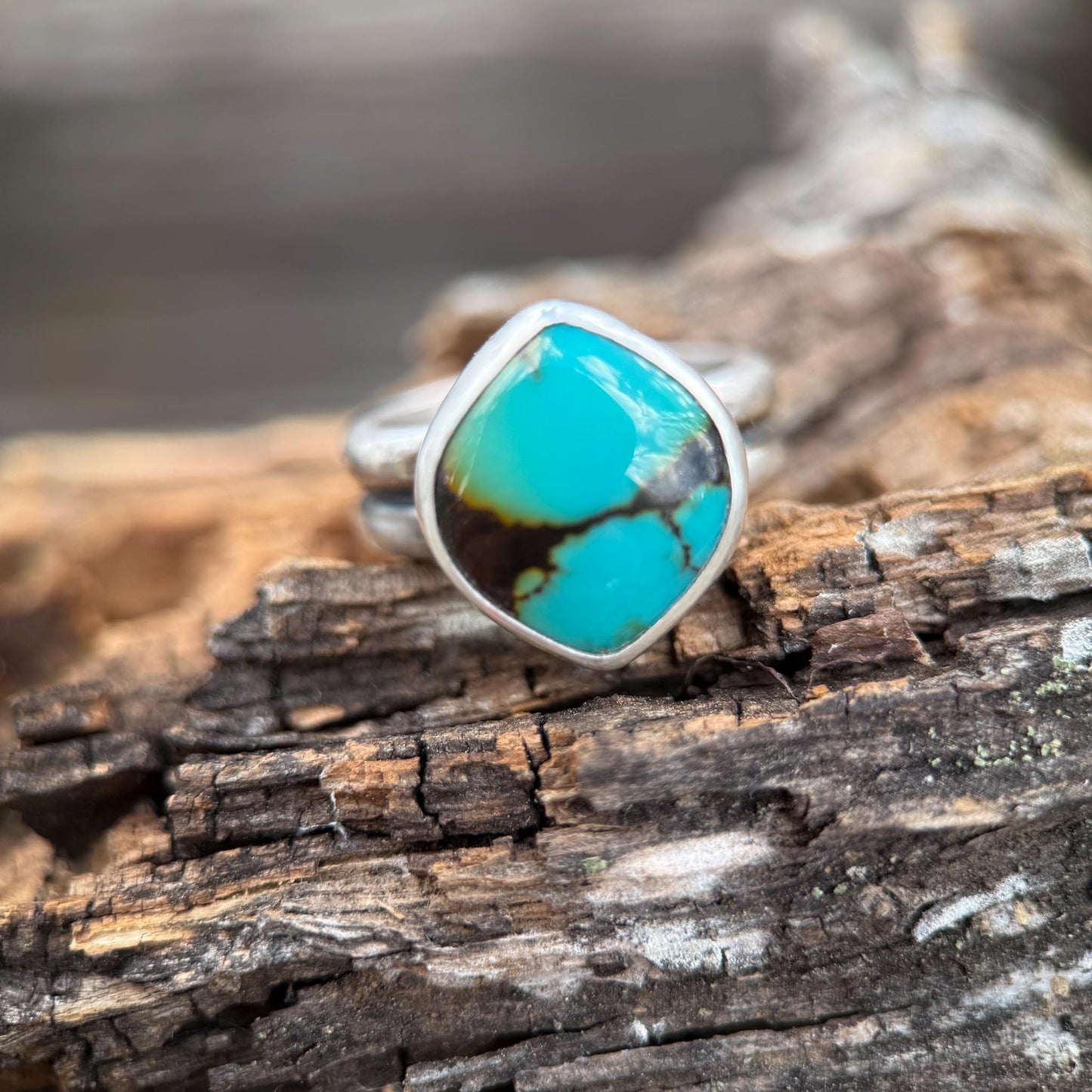 Turquoise ring with silver band on a wooden surface