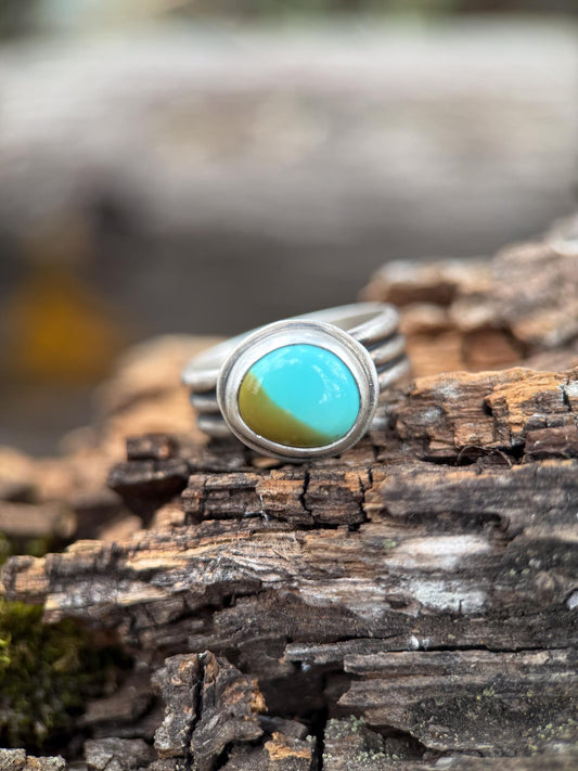 Silver ring with a turquoise stone on a wooden surface