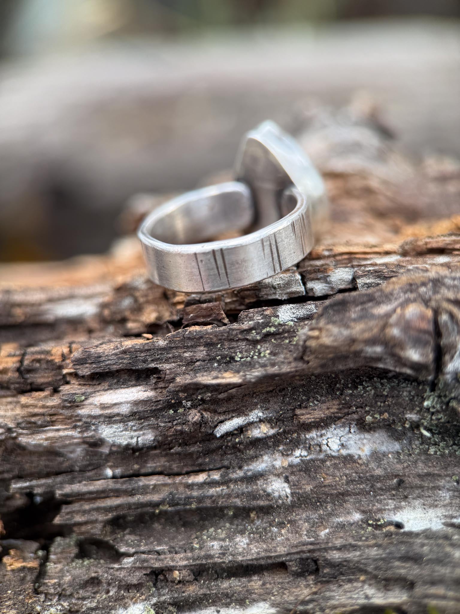 Silver ring on a wooden surface with a natural background