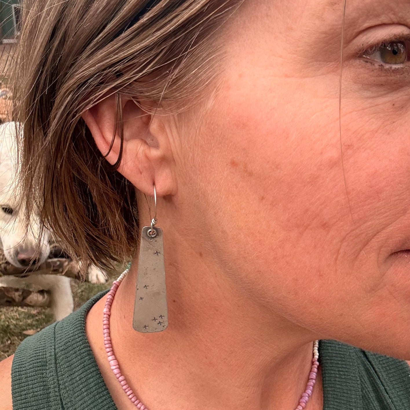 Close-up of a person wearing a silver earring with a blurred background