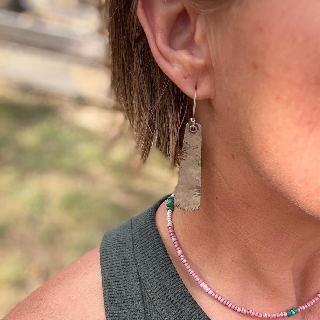 Person wearing a green sleeveless top with a blurred natural background