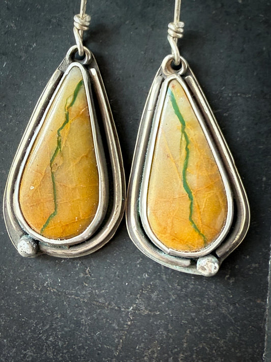 Teardrop-shaped Royston turquoise earrings with yellow and turquoise veined stones in silver frames on a dark background