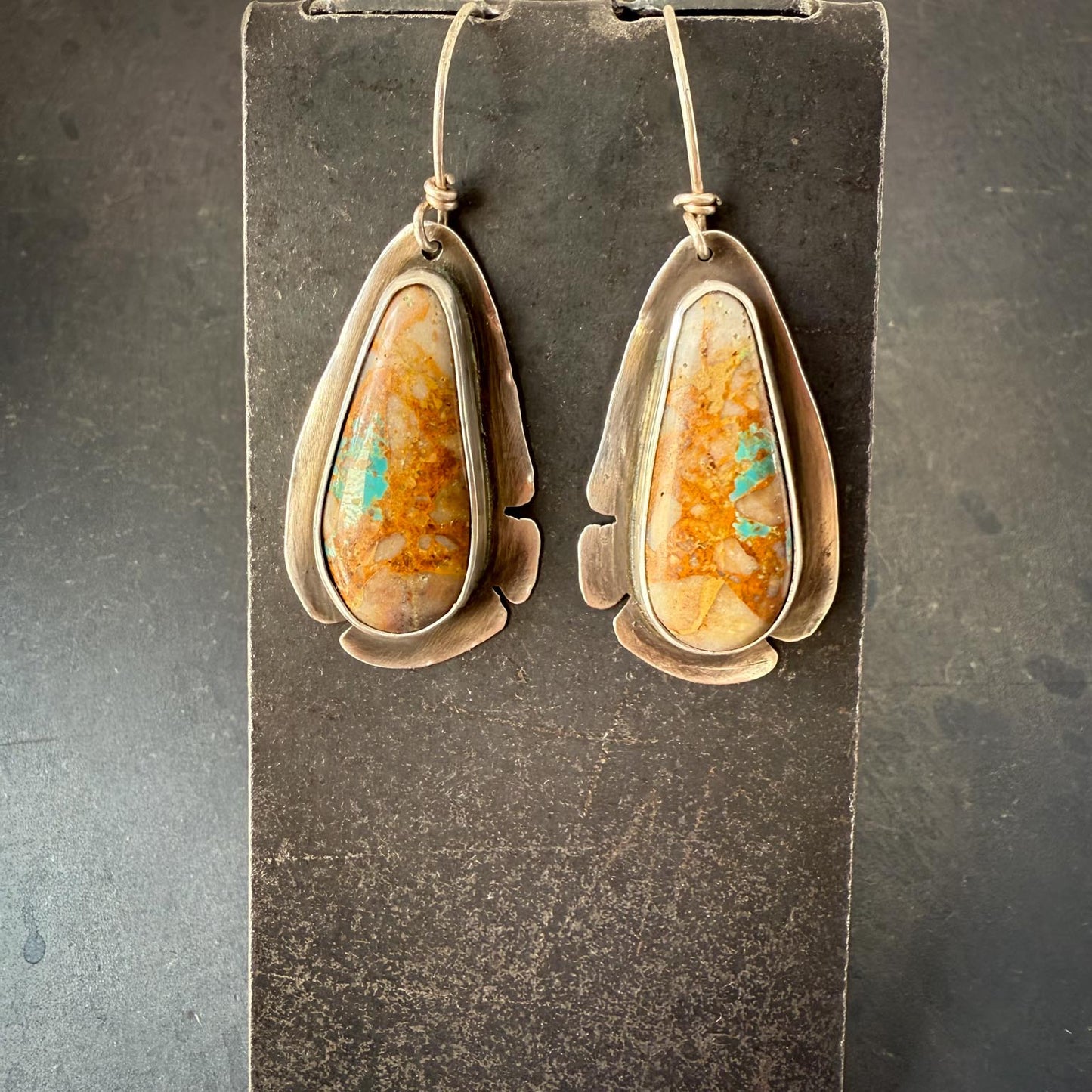 Pair of earrings with teardrop-shaped stones on a dark gray background