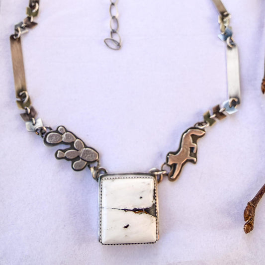 white buffalo turquoise pendant. Unique hand-fabricated chain with small down-dog fox, and tricky pear cactus on either side of the center stone, as part of the chain. Links are made of silver chevrons and one inch strips. Large locking clasp. 