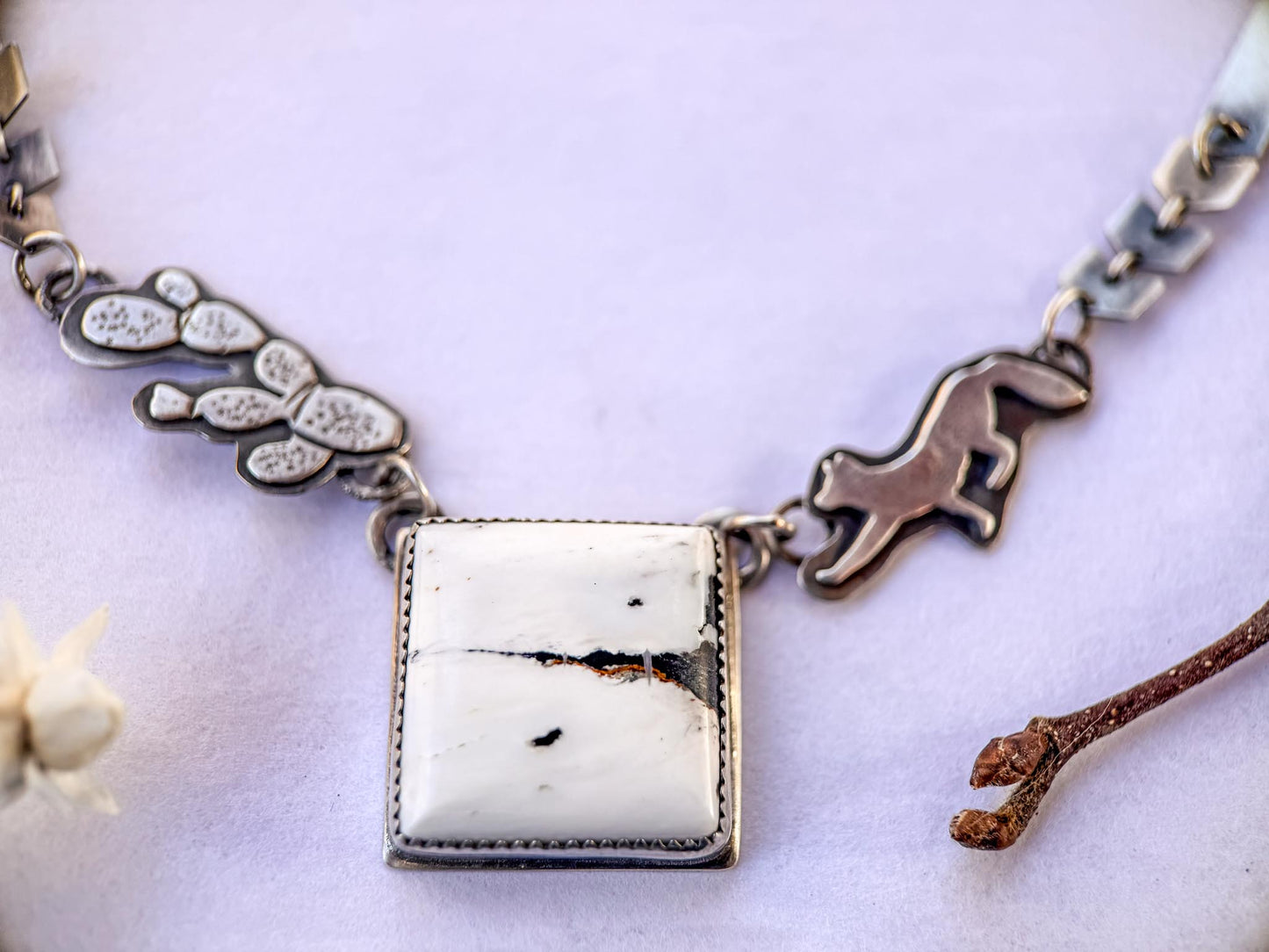 white buffalo turquoise pendant. Unique hand-fabricated chain with small down-dog fox, and tricky pear cactus on either side of the center stone, as part of the chain. Links are made of silver chevrons and one inch strips. Large locking clasp. 