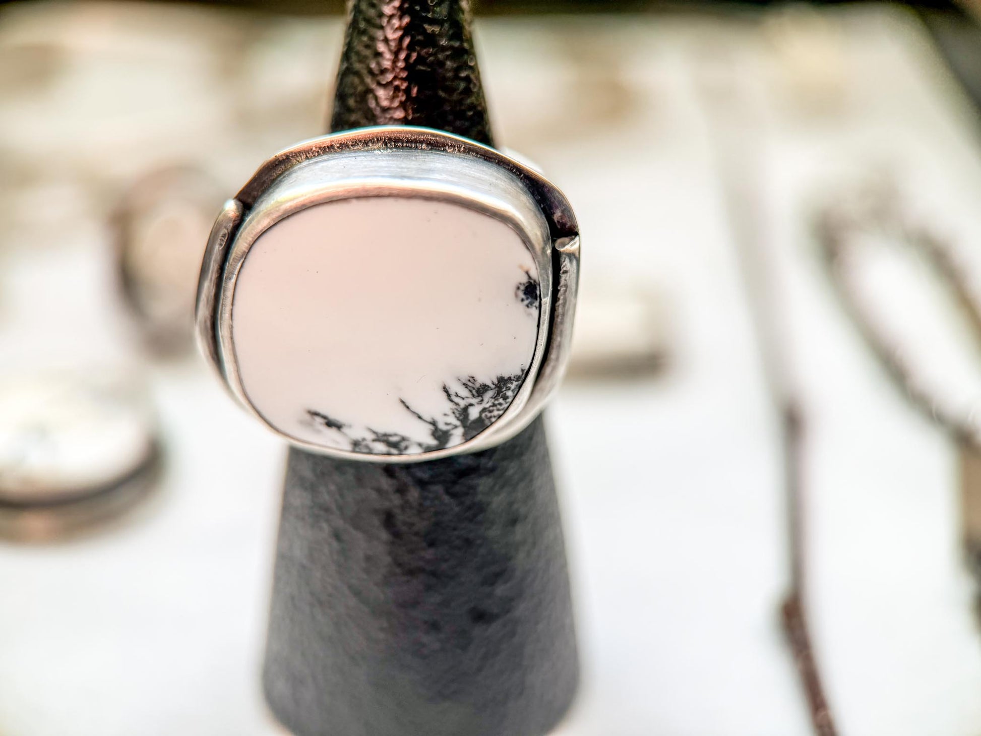 Exceptional white buffalo turquoise stone, organic circular shape, set in sterling silver with a round wire border going around half of the ring. 