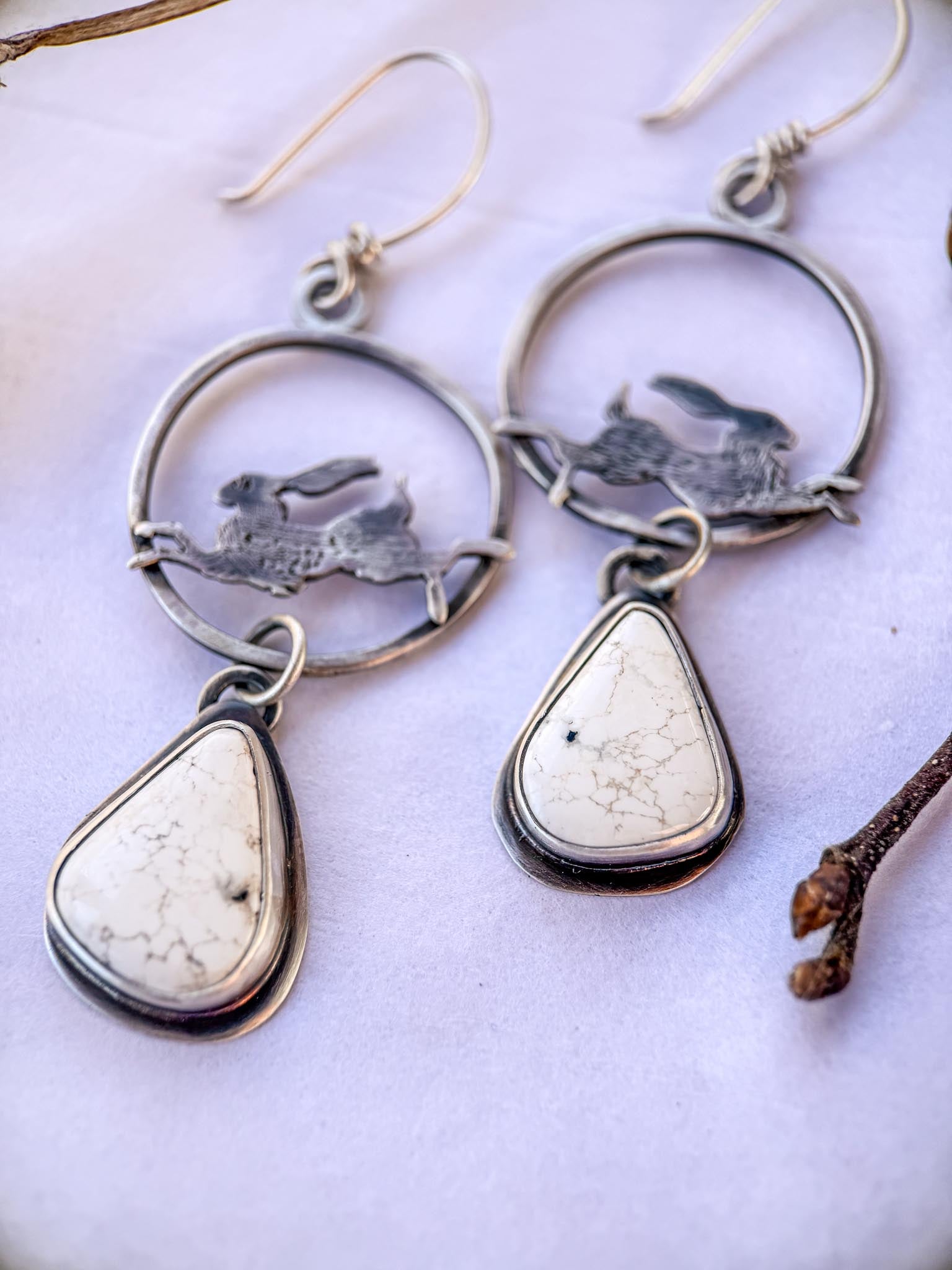white buffalo turquoise teardrop stones, dangling from a lightweight sterling silver hoop, with hand-sawed jackrabbits leaping across the inside hoop.