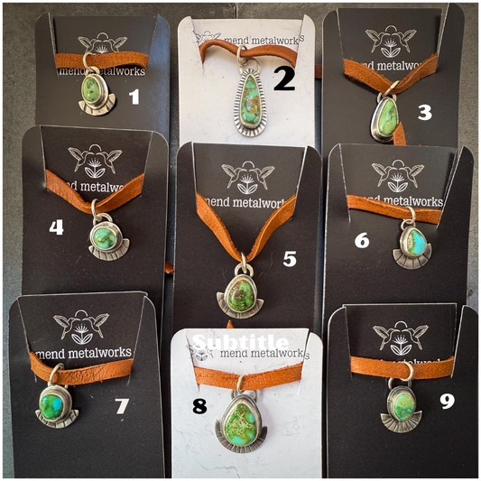 Necklaces with green pendants on brown cord, displayed on cards with 'mend metalworks' branding.