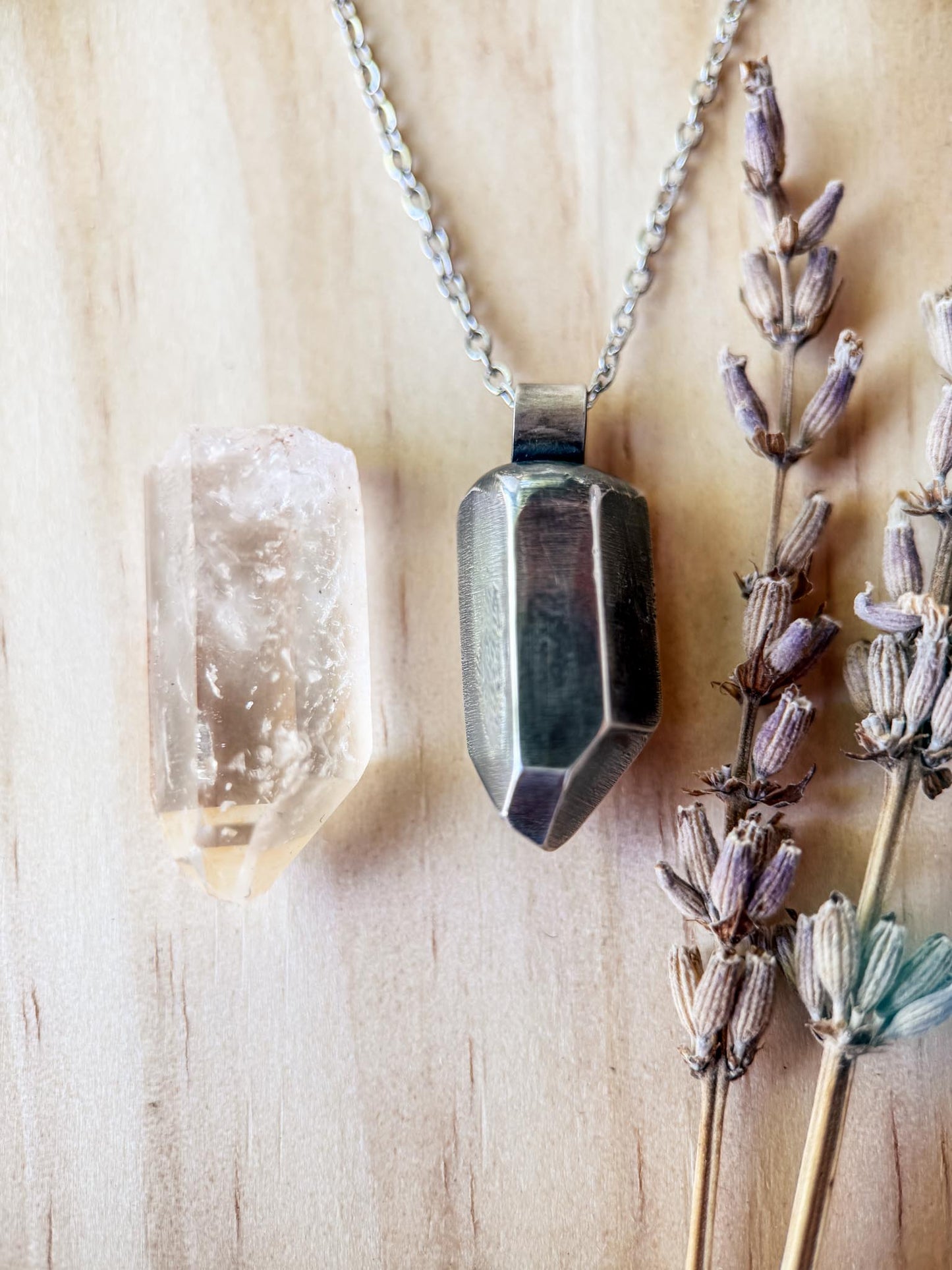 Necklace with a geometric pendant on a wooden surface with crystals and lavender.