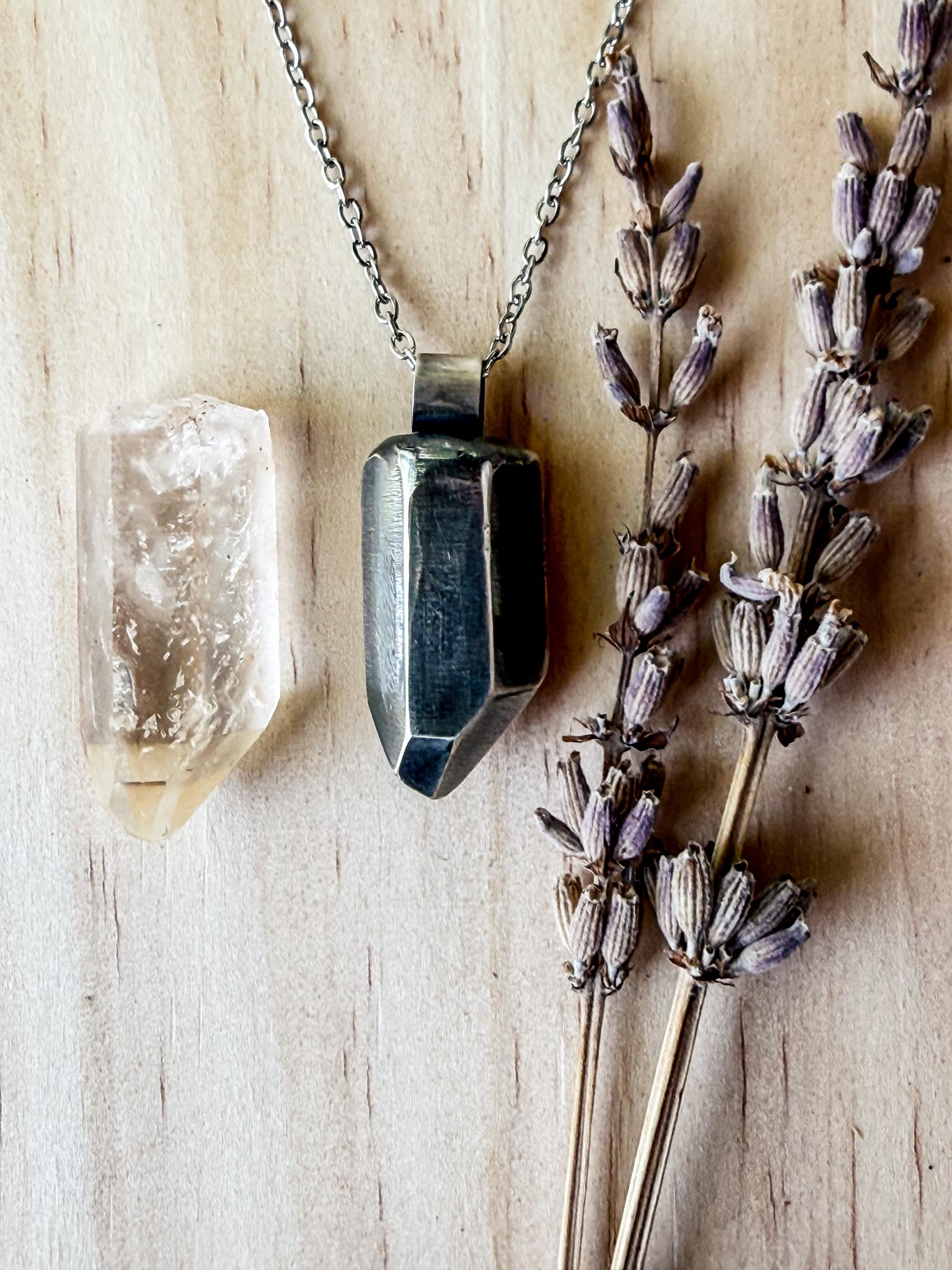 Necklace with geometric pendant on a wooden surface with lavender flowers
