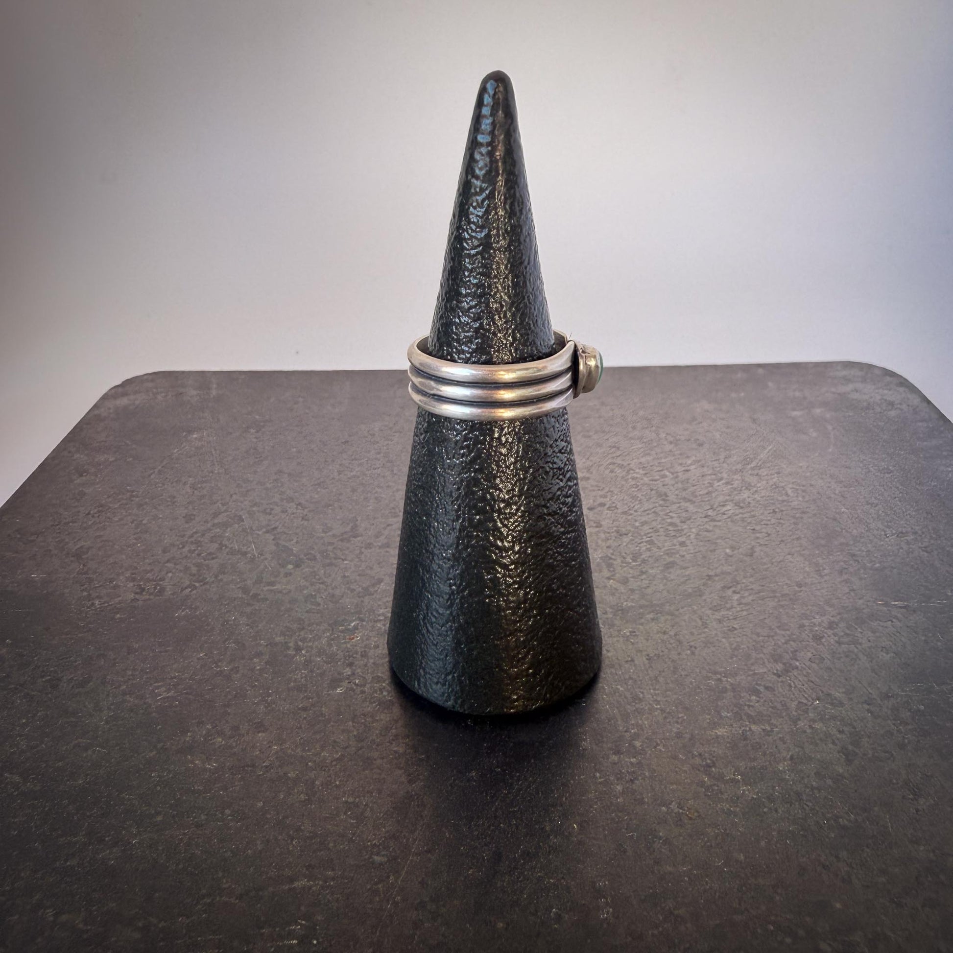 Black textured ring stand with a silver ring on a dark surface