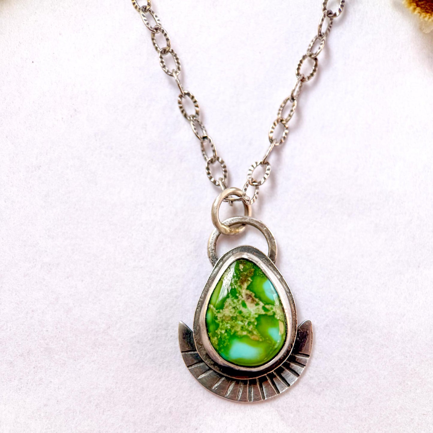 Necklace with a green teardrop pendant on a white background
