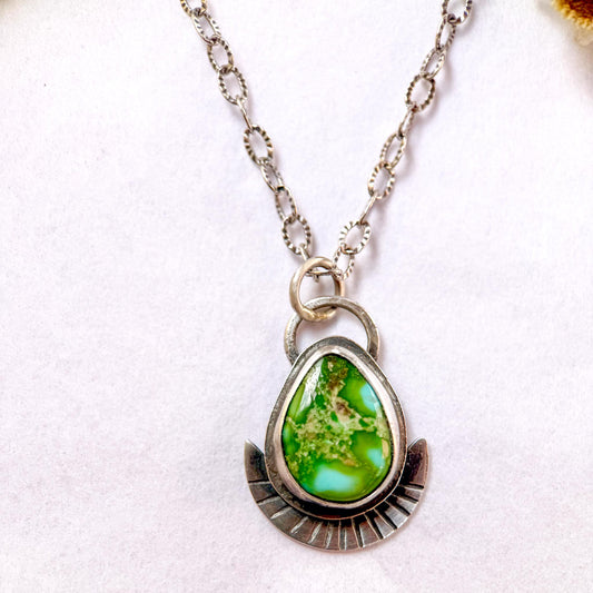 Necklace with a green teardrop pendant on a white background