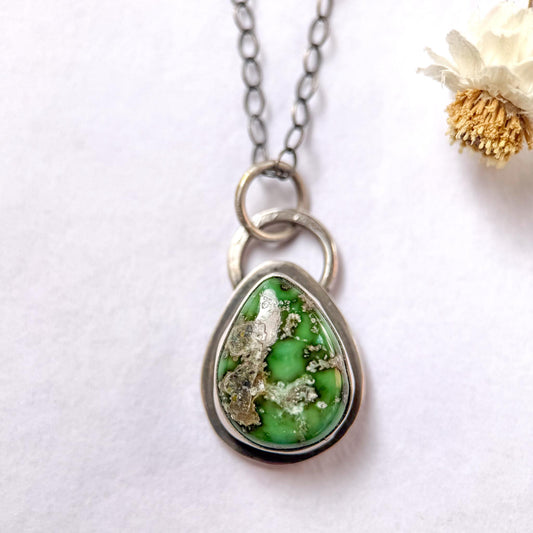Necklace with a green teardrop pendant on a white background