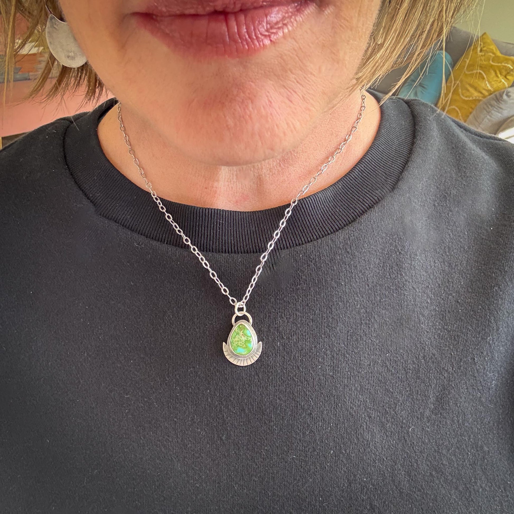 Necklace with a green pendant worn by a person